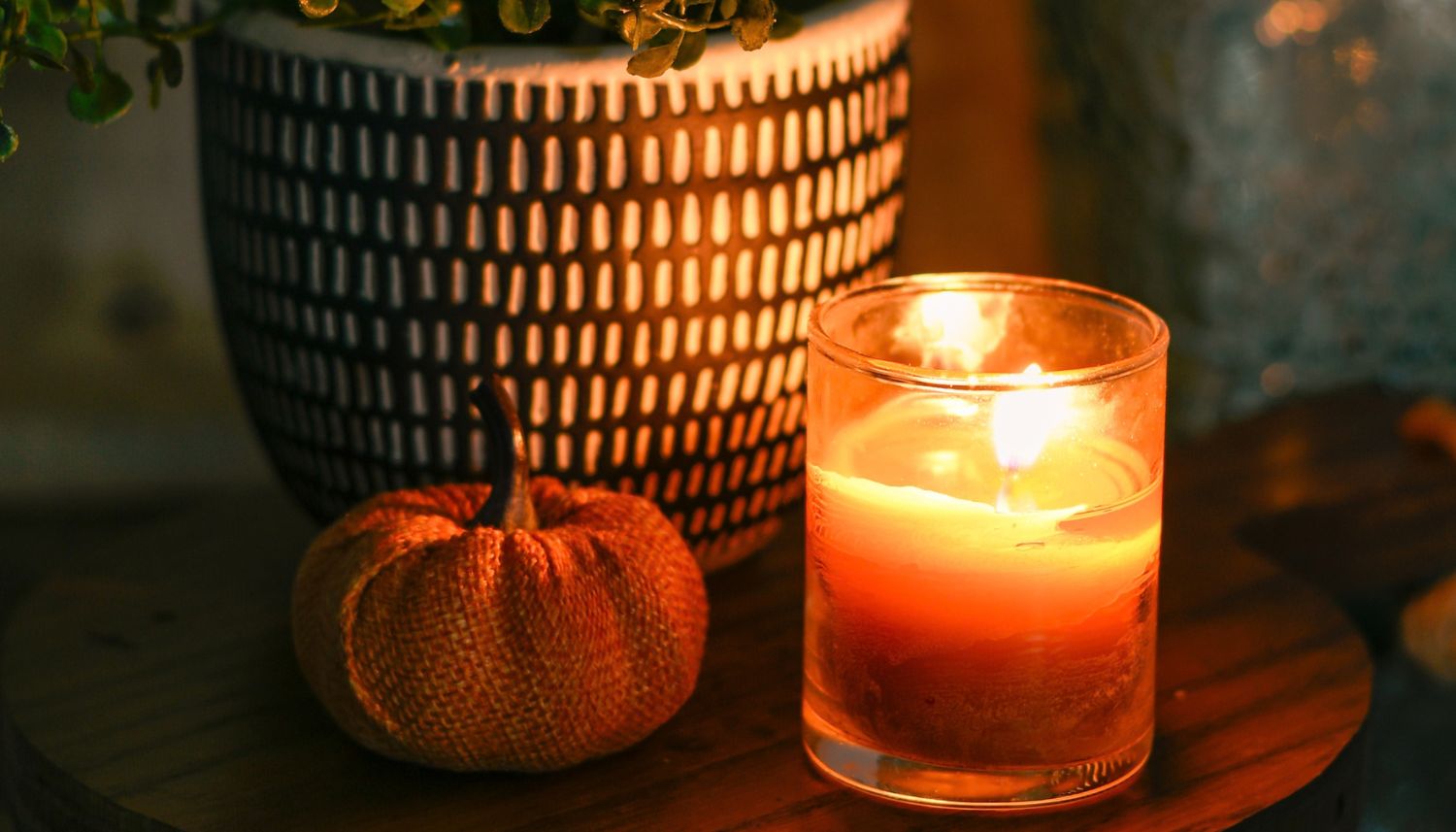 Small Fall Candle Lit next to a small pumpkin and decorative pot