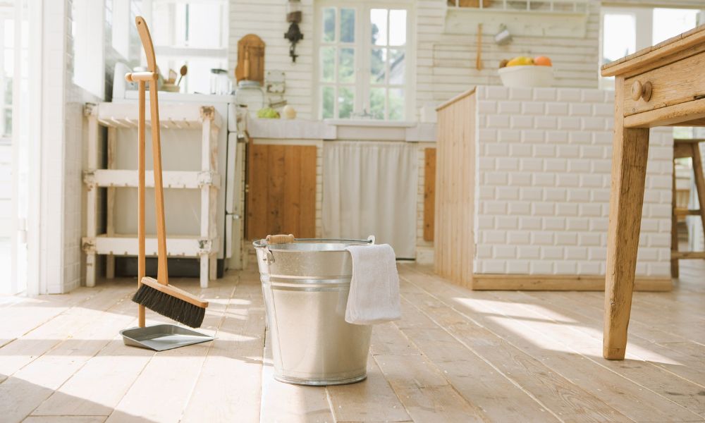 bucket with towel and broom with a dustpan in a clean kitchen